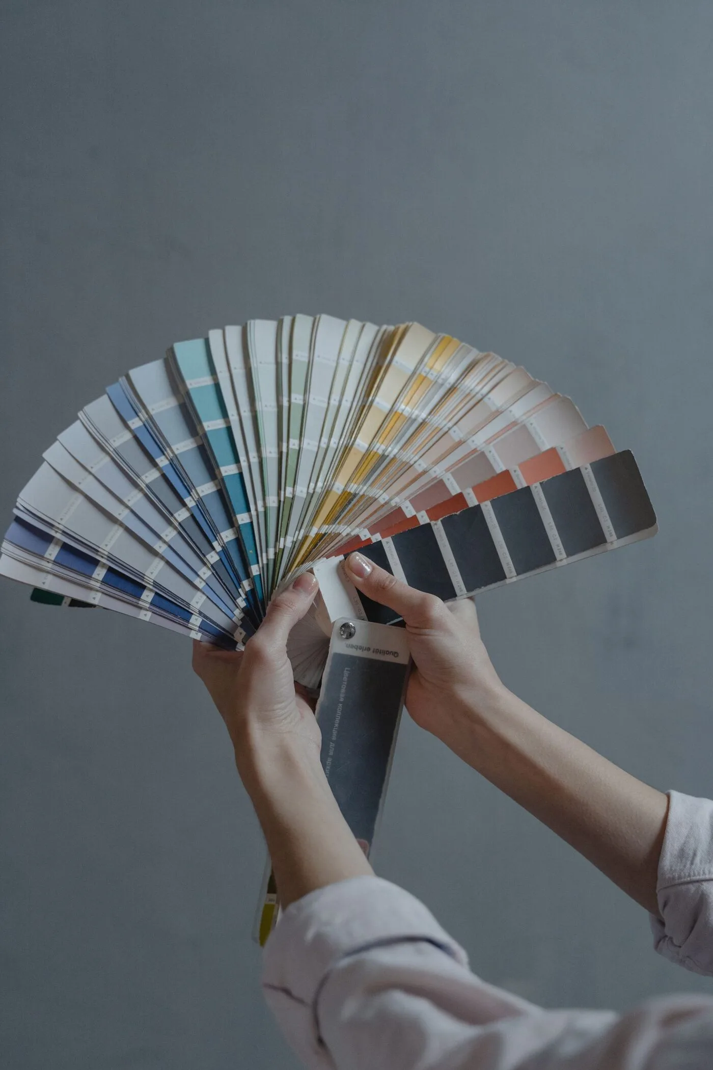 Comparing paint color swatches from a fan deck against a wall during a color consultation