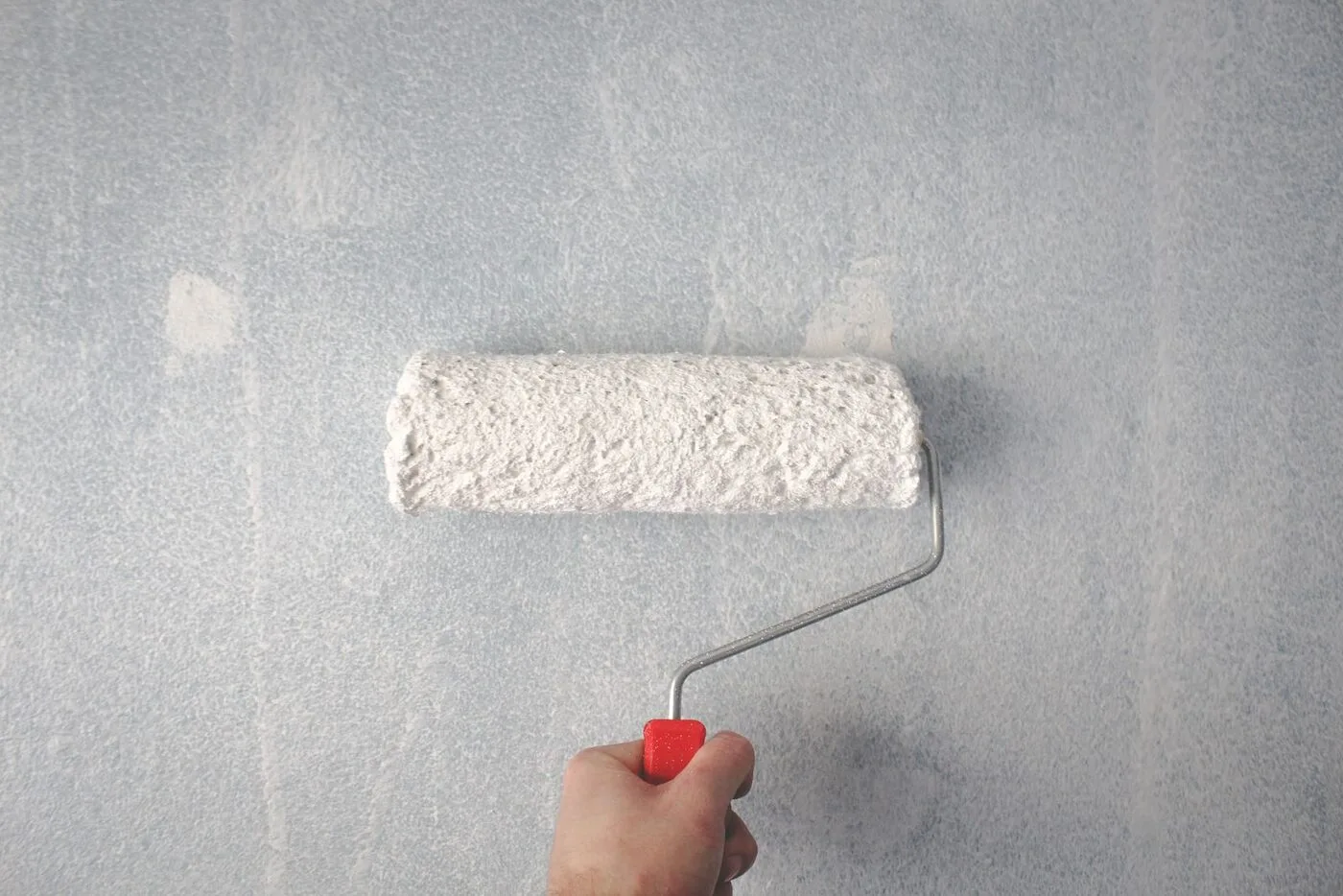 Roller applying a smooth finish coat to a wall